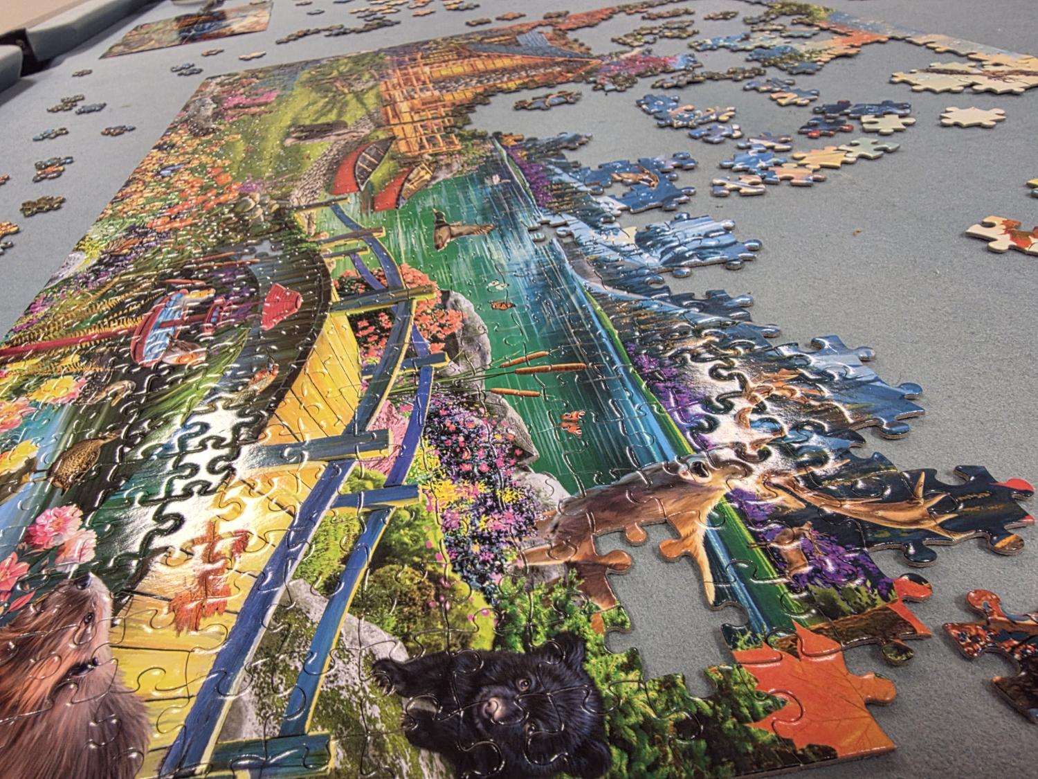 Large wildlife lodge jigsaw in progress, boardwalk over a pond, animals at the edge